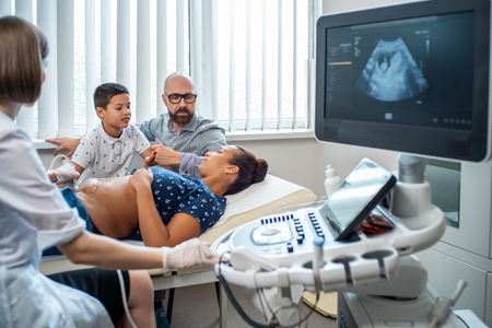 Pregnant woman and her family on utltrasonographic examination at hospitalの写真素材