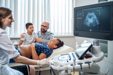 Pregnant woman and her family on utltrasonographic examination at hospitalの写真素材