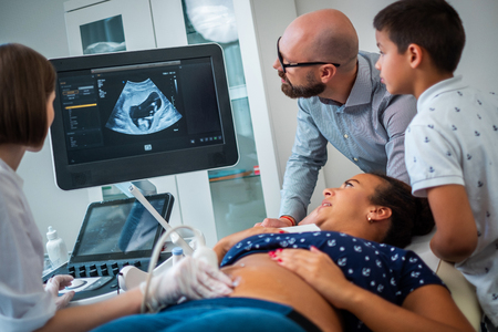 Pregnant woman and her family on utltrasonographic examination at hospitalの写真素材