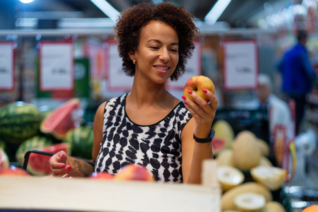Pretty black woman choosing fruits in a grocery storeの写真素材