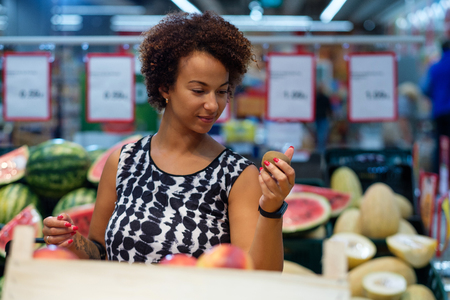 Pretty black woman choosing fruits in a grocery storeの写真素材