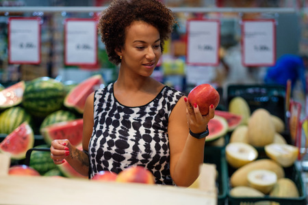 Pretty black woman choosing fruits in a grocery storeの写真素材