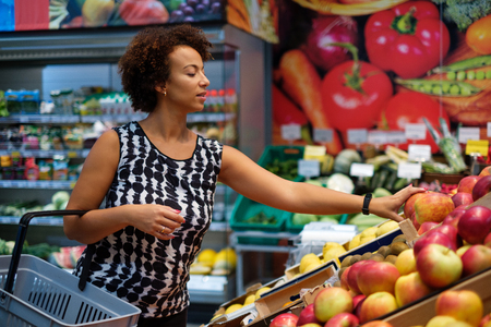 Pretty black woman choosing fruits in a grocery storeの写真素材