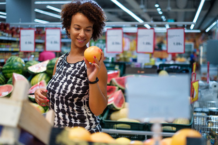 Pretty black woman choosing fruits in a grocery storeの写真素材