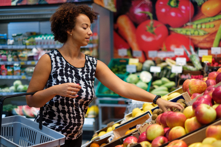 Pretty black woman choosing fruits in a grocery storeの写真素材