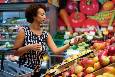 Pretty black woman choosing fruits in a grocery storeの写真素材