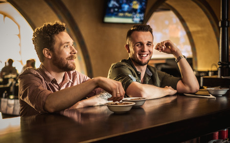 Cheerful friends drinking draft beer in a pubの写真素材
