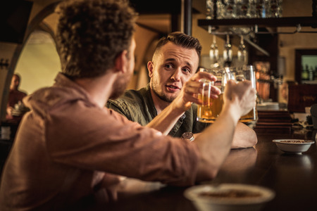 Cheerful friends drinking draft beer in a pubの写真素材