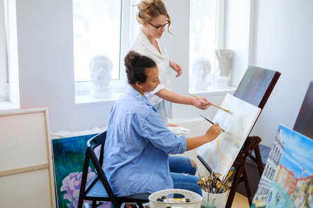 Creative painter and her protege working in a studioの写真素材