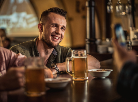 Cheerful friends drinking draft beer in a pubの写真素材