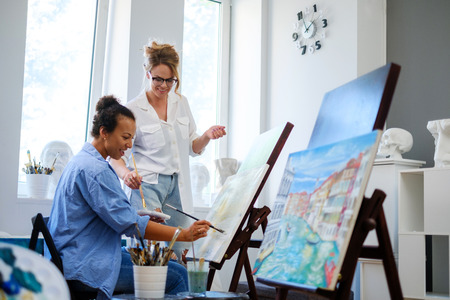 Creative painter and her protege working in a studioの写真素材