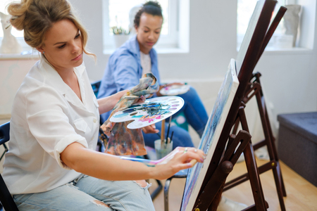 Creative painter and her protege working in a studioの写真素材