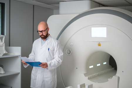 Doctor with a patient medical card near MRI scanner in a hospitalの写真素材