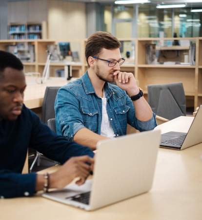 Young men working on a laptops in public libraryの写真素材
