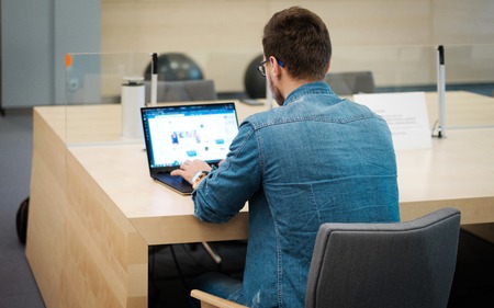 Young man working on a laptop in public libraryの写真素材