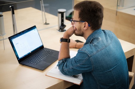 Young man working on a laptop in public libraryの写真素材