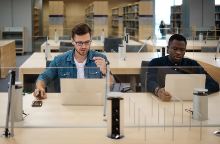 Young men working on a laptops in public libraryの写真素材