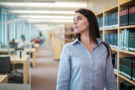 Young woman choosing book in public libraryの写真素材