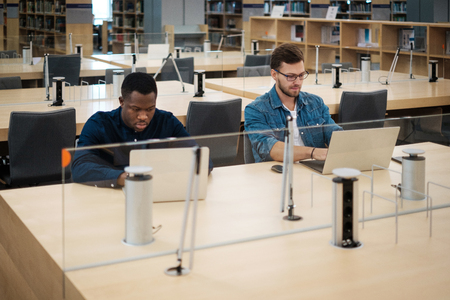 Young men working on a laptops in public libraryの写真素材