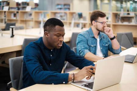 Young men working on a laptops in public libraryの写真素材