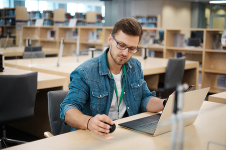 Young man working on a laptop in public libraryの写真素材