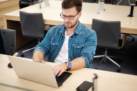 Young man working on a laptop in public libraryの写真素材