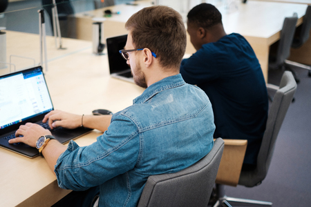 Young men working on a laptops in public libraryの写真素材