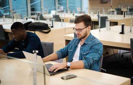 Young men working on a laptops in public libraryの写真素材
