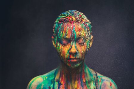 Young woman covered with a colourful paintの写真素材