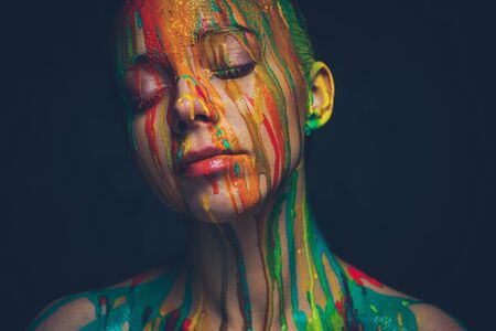 Young woman covered with a colourful paintの写真素材