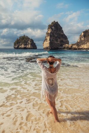 Woman walking on a beach at Diamond Bay, Nusa Penida island, Indonesiaの写真素材
