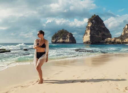 Woman walking on a beach at Diamond Bay, Nusa Penida island, Indonesia.の写真素材