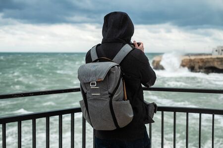Photographer taking picture of a stormy sea in Polignano a Mare, Italy.