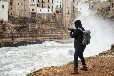 Photographer taking picture of a stormy sea in Polignano a Mare, Italy.の写真素材