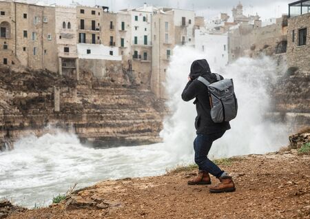 Photographer taking picture of a stormy sea in Polignano a Mare, Italy.の写真素材