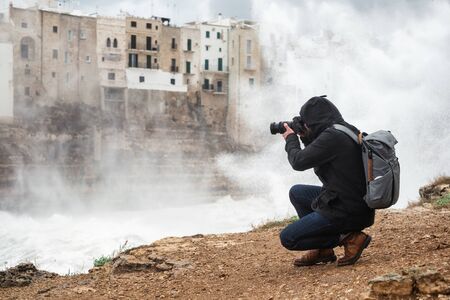 Photographer taking picture of a stormy sea in Polignano a Mare, Italy.の写真素材