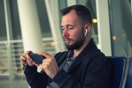 Man wearing wireless earphones looking at screen of smartphone