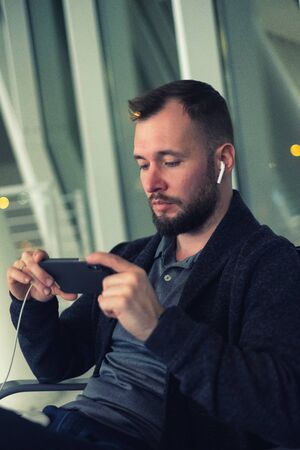 Man wearing wireless earphones looking at screen of smartphone