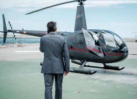 Businessman talking over the phone near private helicopter.の写真素材