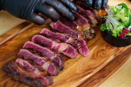 Serving freshly cooked beef steak on a wooden boardの写真素材