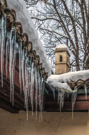 Melting Icicles hanging from the facade of the old buildingの写真素材