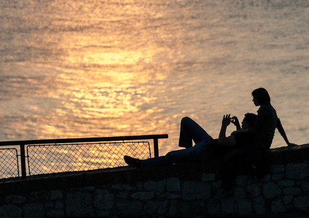 Young couple watching and photographing the sunsetの写真素材
