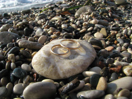Gold wedding rings placed upon pebblesの写真素材