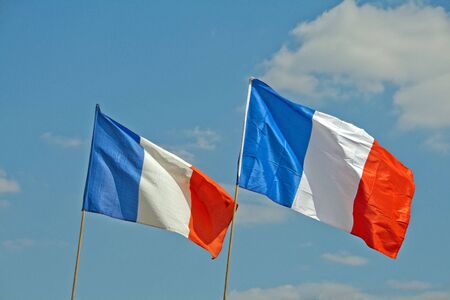 two french flags fluttering in the sky of paris (france)の写真素材
