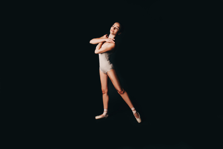 Ballet dancer in beige tights on a black background. Place for your text.の写真素材