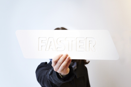 Woman holding a white sign saying faster. Shallow depth of field with focus on the sign and handの写真素材