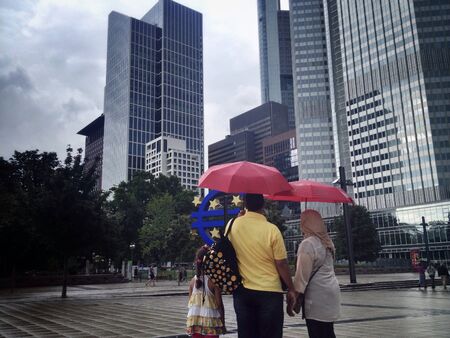 Family with umbrella on rainy day in cityの素材