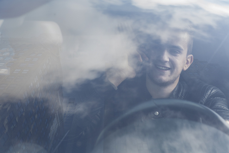 young man in car with reflections in windowの写真素材