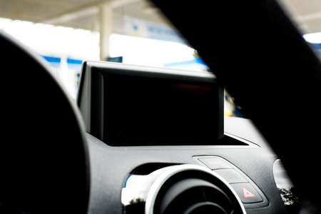 Detailed view of a black dashboard in a car. The display is off. Blurred in the front is a part of the steering wheel.の写真素材