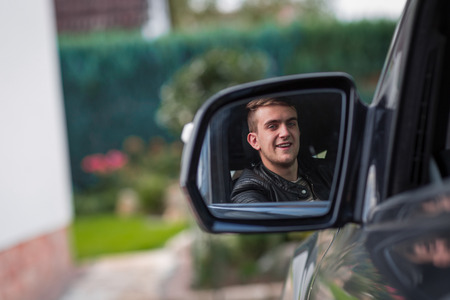 happy young blonde adult inside of a car. happy to have his new licence.
